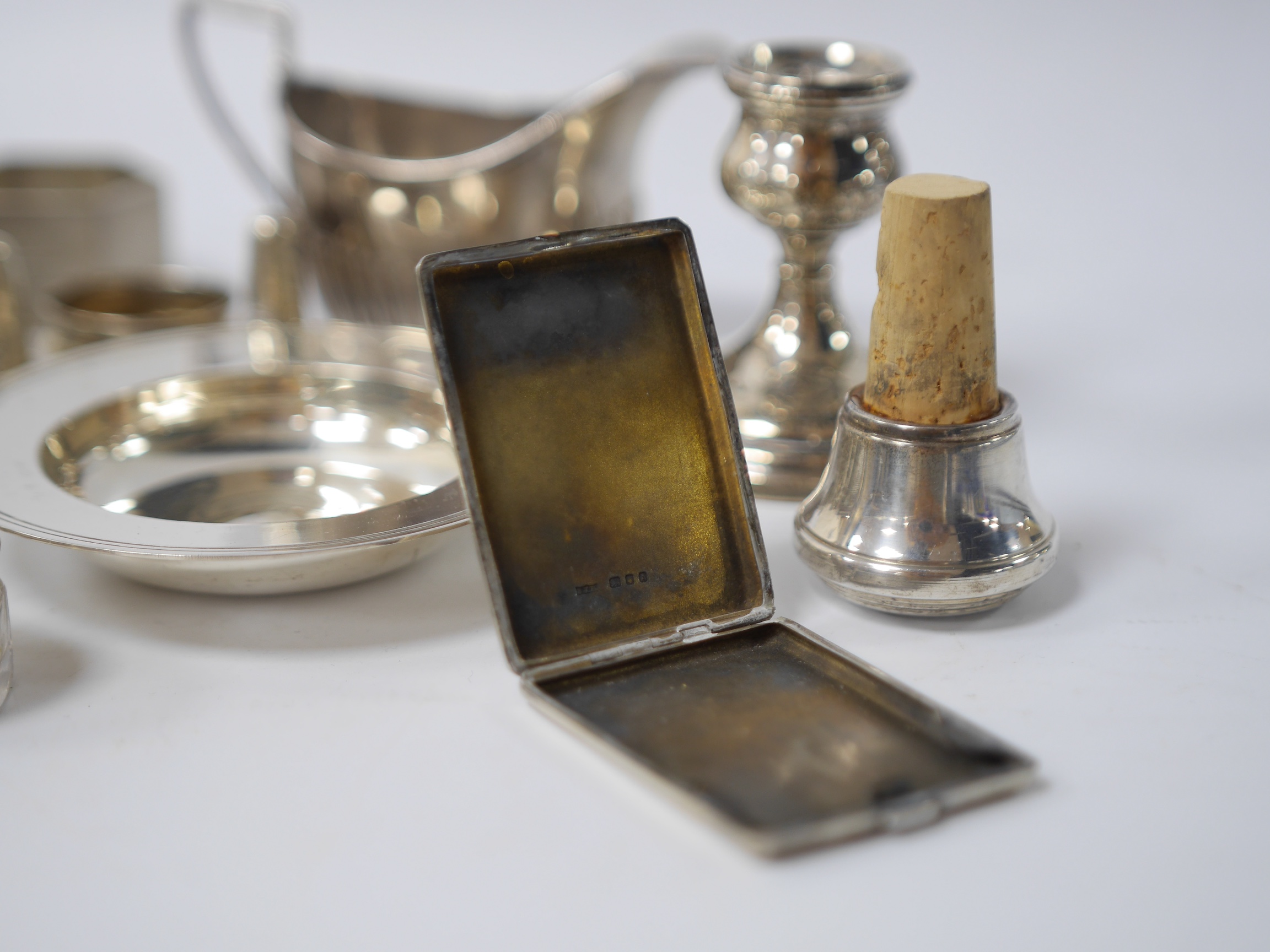 Small silver including two cream jugs, one demi-fluted, Birmingham, 1894, a dish, a dwarf candlestick, napkin rings, toilet jars, stopper, pepperette and extinguisher. Condition - poor to fair to good